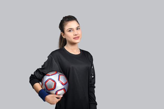 donne sportive in possesso di footballl e guardando il modello pakistano indiano davanti