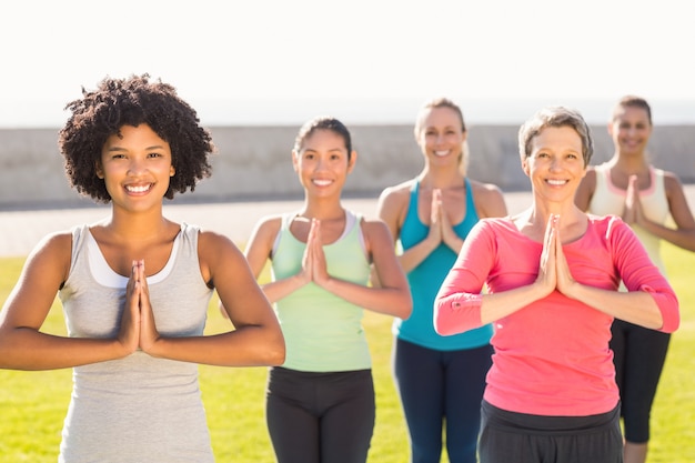 Donne sportive sorridenti che fanno posizione di preghiera nella classe di yoga