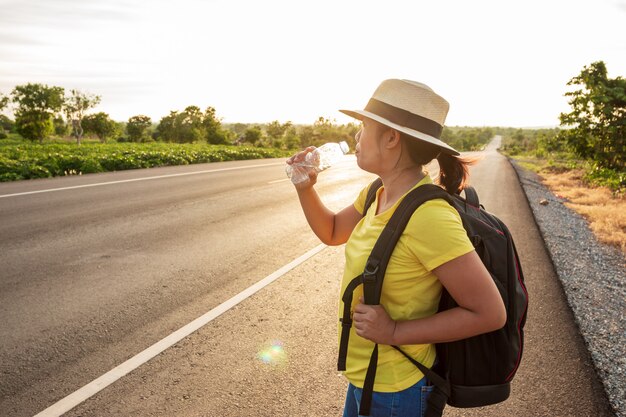 Donne zaino in spalla turisti, acqua potabile in autostrada, con la luce dorata del sole.