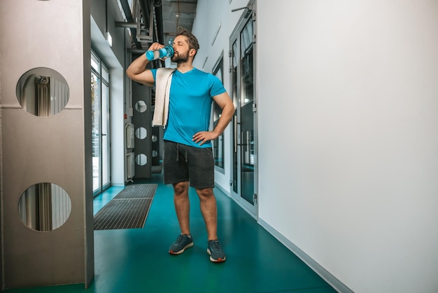 Dopo l'allenamento. Acqua potabile del giovane atleta dopo l'allenamento estenuante