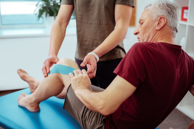 Dopo l'infortunio. Simpatico uomo anziano che segue un corso di terapia riabilitativa dopo un infortunio