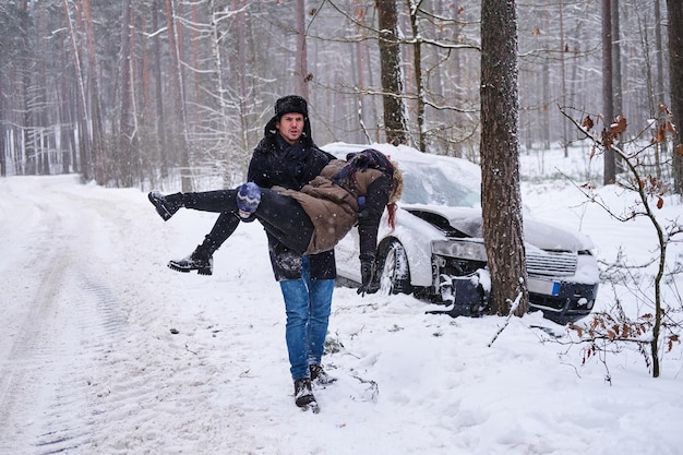 Dopo la cotta d'auto nella foresta invernale, l'uomo serio e sicuro di sé tiene una donna ferita.