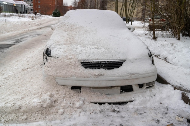 Dopo la rimozione della neve l'auto coperta di neve su una strada invernale