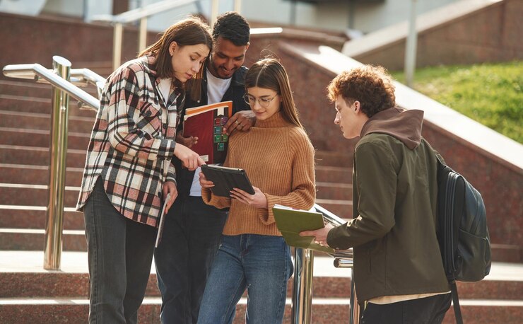 Foto dopo le lezioni, quattro giovani studenti in abiti casuali sono insieme all'aperto.
