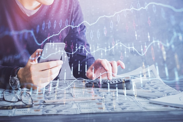 Doppia esposizione delle mani dell'uomo che tiene e utilizza un dispositivo digitale e disegno di grafici forex concetto di mercato finanziario