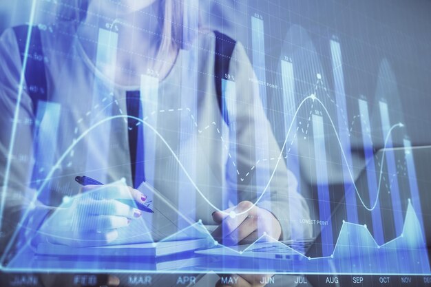 Doppia esposizione delle mani della donna d'affari che digitano sul computer e sul disegno dell'ologramma del grafico finanziario Concetto di analisi del mercato azionario