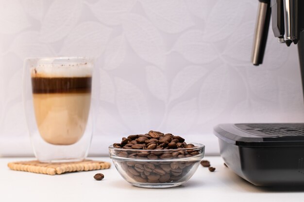 Doppio bicchiere termico con cappuccino accanto a chicchi di Arabica Appetitoso caffè con schiuma di latte