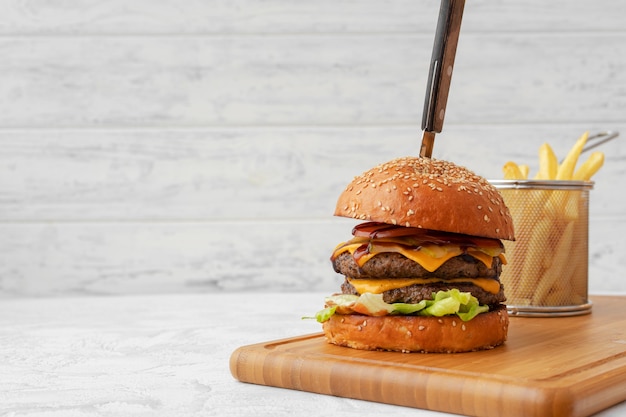 Doppio cheeseburger servito sulla tavola di legno su sfondo bianco sfocato