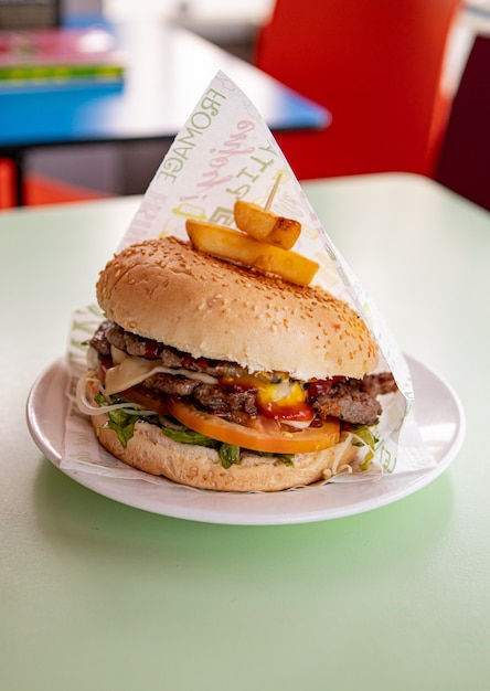 Doppio cheeseburger succoso con pancetta, pomodoro, insalata e salse. Verticale con copia spazio