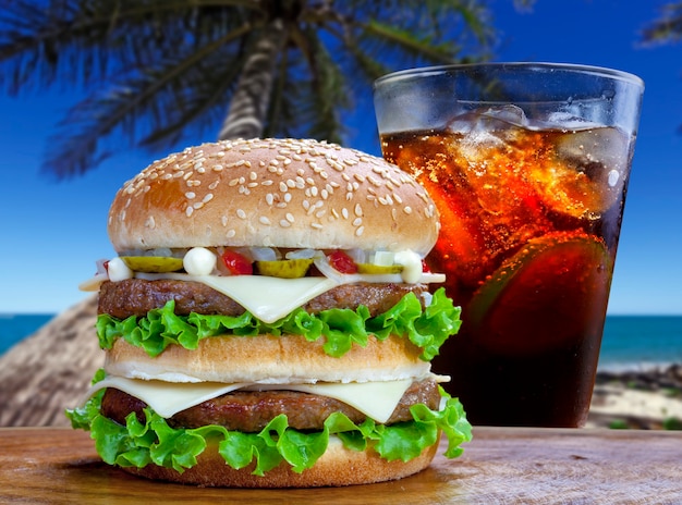 Doppio hamburger con soda cola su una spiaggia d'estate