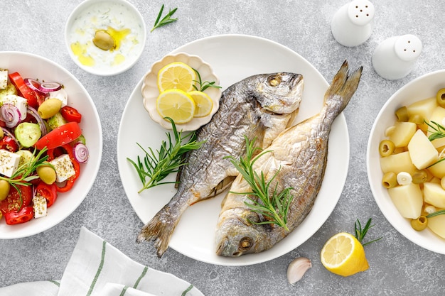 Dorada pesce orata al forno verdure fresche insalata greca patate bollite con aglio e olive e salsa tzatziki Cibo sano Dieta mediterranea