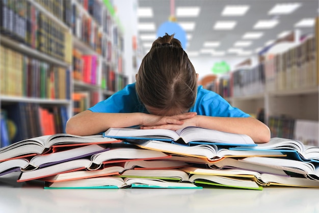 Dormire in biblioteca. Tipo caucasico stanco che fa pisolino sulla pila di libri,