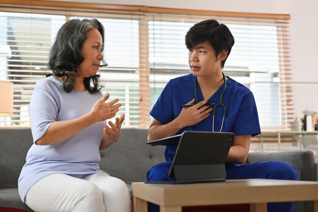 Dottore asiatico che indica un tablet digitale che condivide i risultati dei test di salute dei risultati di laboratorio dei risultati del controllo medico con una paziente anziana