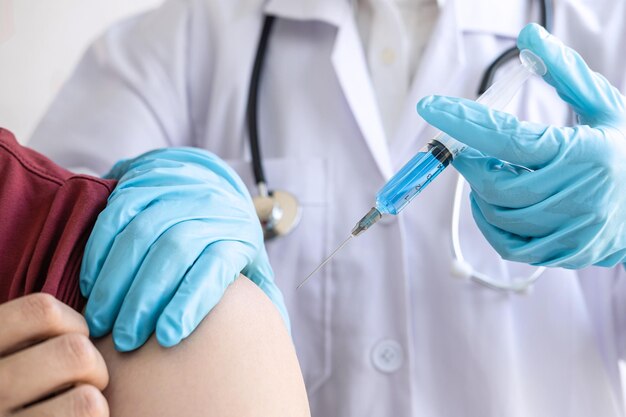 Dottore che inietta al paziente la vaccinazione per prevenire la pandemia della malattia influenza o del virus dell'influenza in clinica