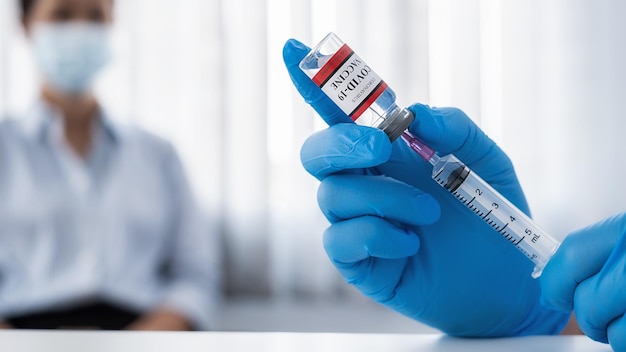 Dottore che riempie una siringa di farmaci con il vaccino contro il coronavirus COVID-19 che prende per una donna