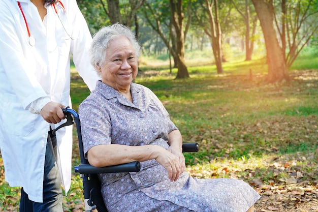 Dottore che spinge una donna sorridente seduta in sedia a rotelle