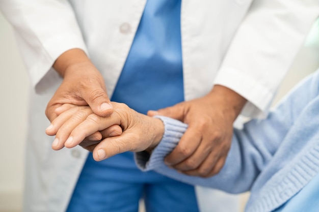 Dottore che tiene la mano e aiuta una paziente anziana in ospedale
