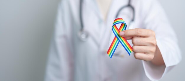 Dottore con nastro arcobaleno LGBTQ per sostenere la comunità lesbica gay bisessuale Transgender e Queer e felice concetto del mese dell'orgoglio