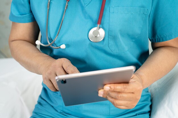 Dottore con tablet digitale per cercare dati per il trattamento del paziente nel reparto ospedaliero di infermieristica sano concetto medico forte