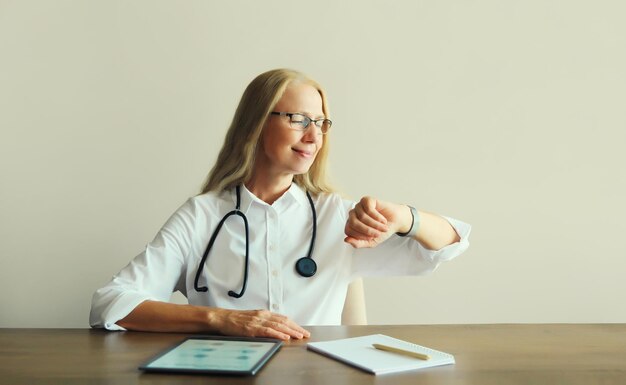 Dottore donna con stetoscopio documenti computer tablet digitale seduto alla scrivania nell'ufficio della clinica