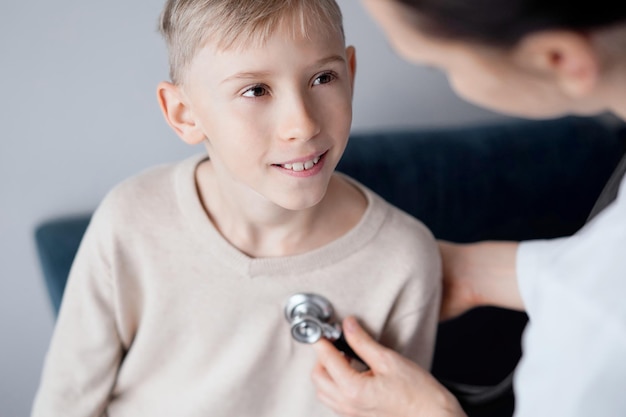 Dottore e bambino sorridente paziente a casa ispezione medica.