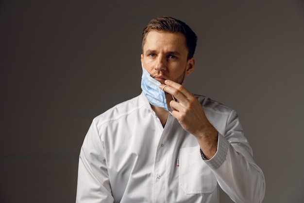 Dottore in maschera medica per la protezione contro il covid-19. Bello uomo con indosso una veste medica