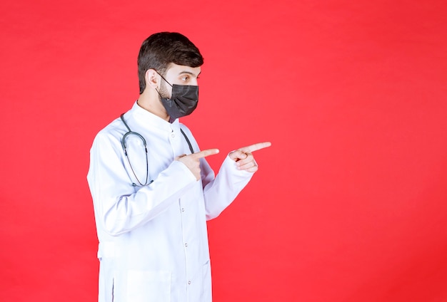Dottore in maschera nera con stetoscopio sul collo.