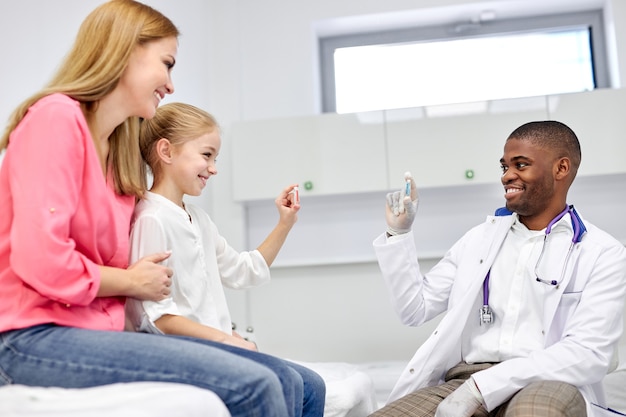 dottore maschio nero ha una bella chiacchierata con una ragazzina, mostrandole capsule moderne colorate, dispone, lavora con i bambini in ospedale