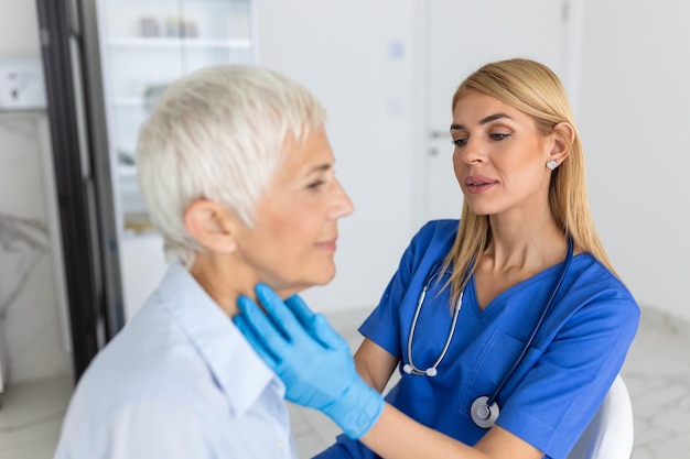 Dottoressa amichevole che indossa guanti che controlla il mal di gola o le ghiandole tiroidee che tocca il collo di una paziente anziana che visita l'ufficio della clinica Concetto di prevenzione del cancro della tiroide