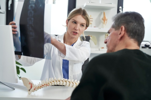 Dottoressa caucasica che analizza un paziente con una malattia della colonna vertebrale
