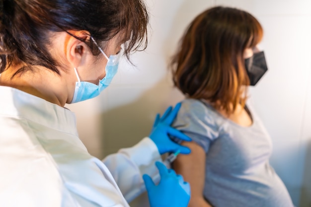 Dottoressa che applica il vaccino contro il coronavirus a una donna incinta. Anticorpi, immunizza la popolazione.