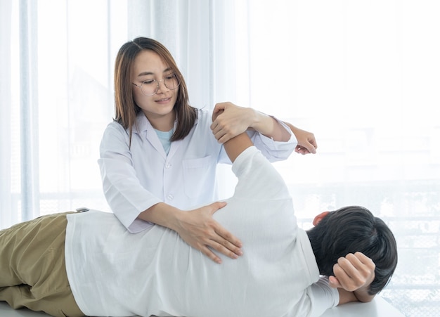Dottoressa che fa terapia fisica Estendendo la schiena di un paziente di sesso maschile.
