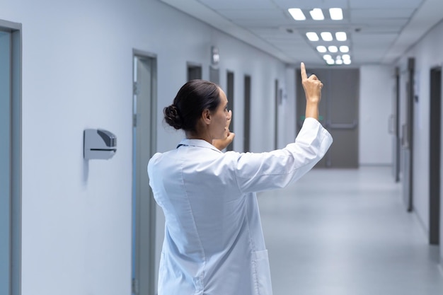 Dottoressa che finge di toccare uno schermo invisibile nel corridoio dell'ospedale