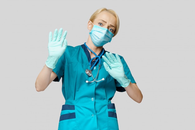 Dottoressa che indossa maschera protettiva e guanti in lattice spaventati e stressati