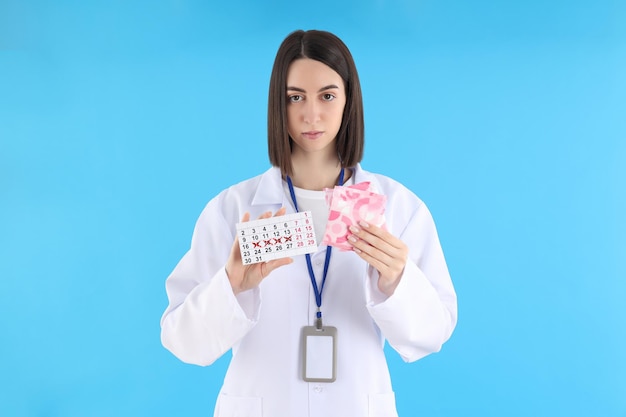 Dottoressa con calendario mestruale e tamponi su sfondo blu