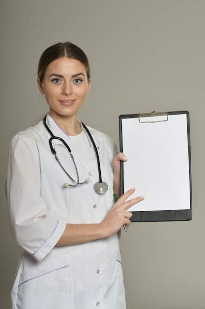 Dottoressa con una cartella, in piedi isolata su sfondo grigio