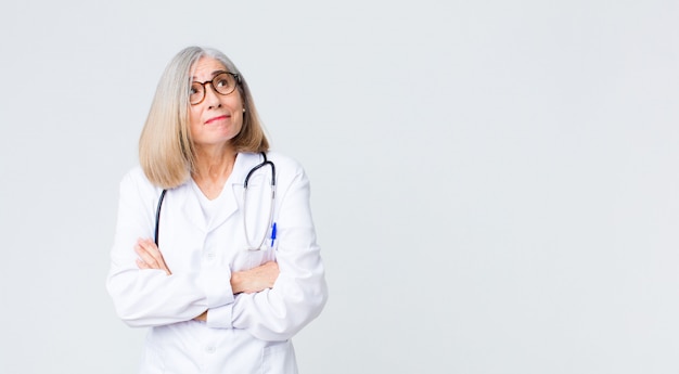 Dottoressa di mezza età che scrolla le spalle, sentendosi confusa e incerta, dubitando con le braccia incrociate e lo sguardo perplesso