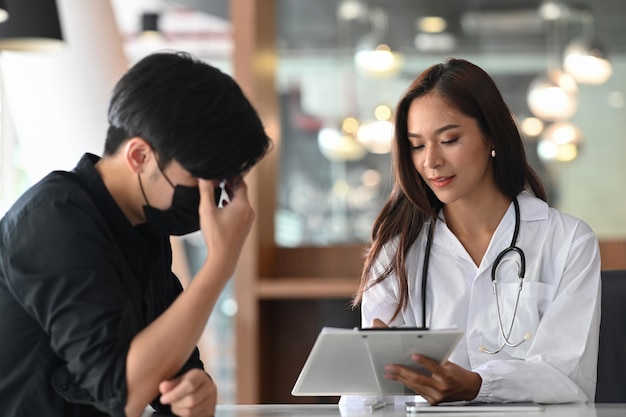 Dottoressa in uniforme bianca che spiega e suggerisce alcune informazioni al paziente maschio depresso.