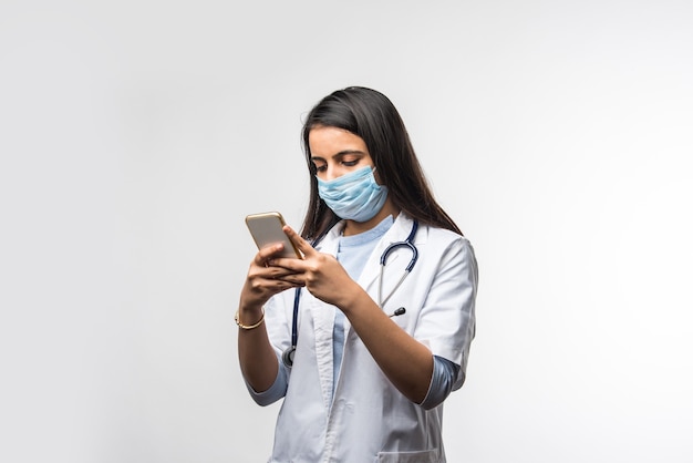Dottoressa indiana che parla su smartphone Eccitata, indossa una maschera medica nella pandemia di coronavirus