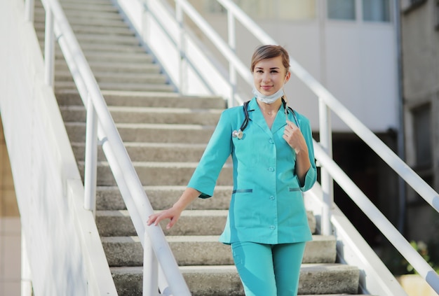 Dottoressa o infermiera che indossa una maschera protettiva e indumenti medici, uno stetoscopio intorno al collo