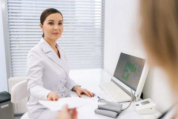 Dottoressa professionista che dà una prescrizione a un paziente irriconoscibile al check-up