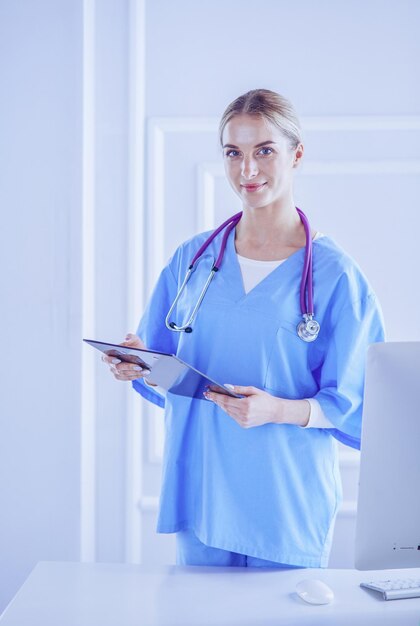 Dottoressa sorridente con una cartella in uniforme in piedi