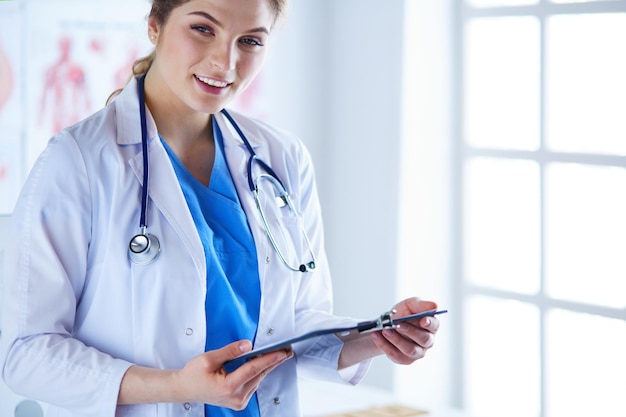 Dottoressa sorridente con una cartella in uniforme in piedi