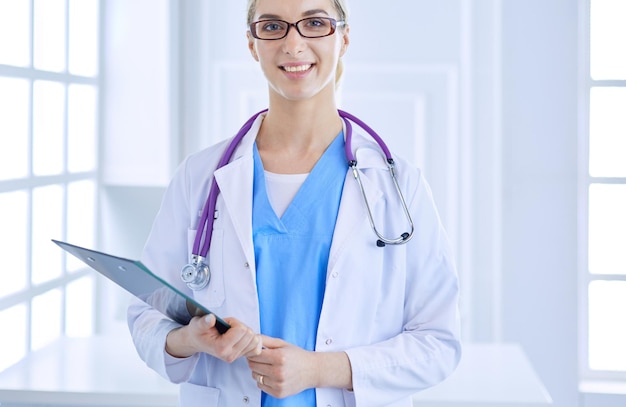 Dottoressa sorridente con una cartella in uniforme in piedi