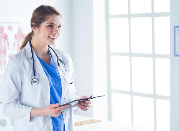 Dottoressa sorridente con una cartella in uniforme in piedi