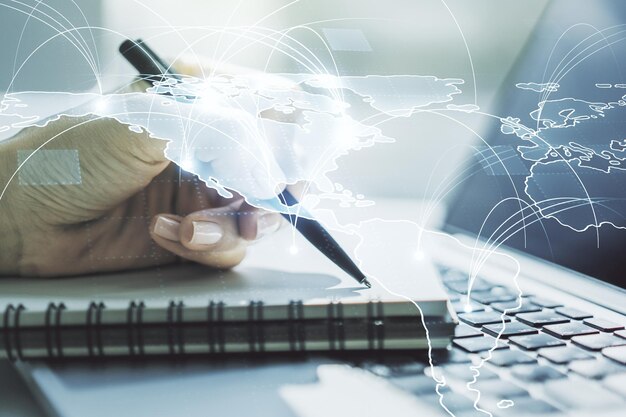 double exposure of abstract digital world map with connections and hand writing in notepad on background with laptop big data and blockchain concept