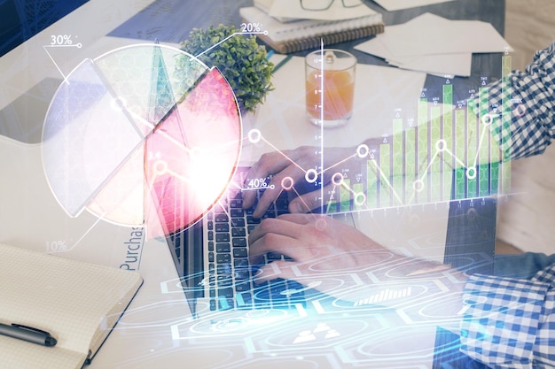 double exposure of graph with man typing on computer in office on background concept of hard work