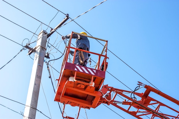 dovere del lineman che lavora la linea elettrica fissa sul cavo elettrico con piattaforme aeree di lavoro