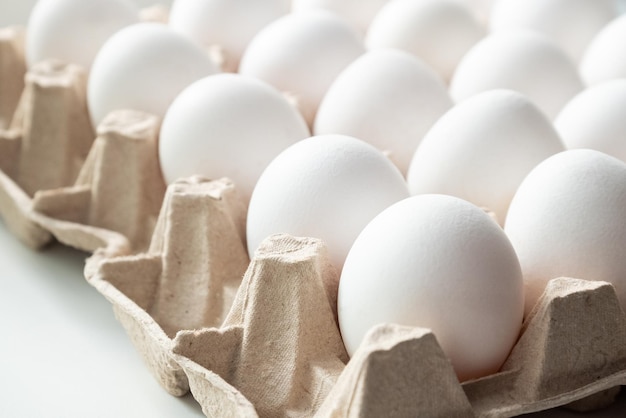 Dozzina di uova di gallina bianche fresche in vassoio di carta