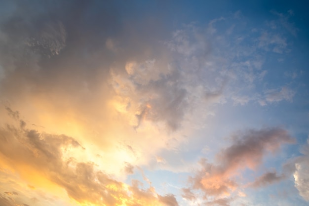 Drammatica immagine del paesaggio al tramonto con nuvole gonfie illuminate dal sole al tramonto arancione e dal cielo blu.